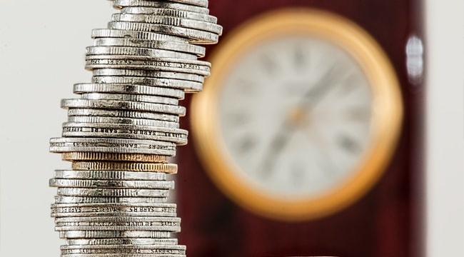 Stack of coins in front of a clock